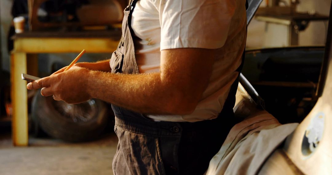 Mechanic Writing Work Order on Notepad while Holding Pencil in Greasy Garage Workshop
