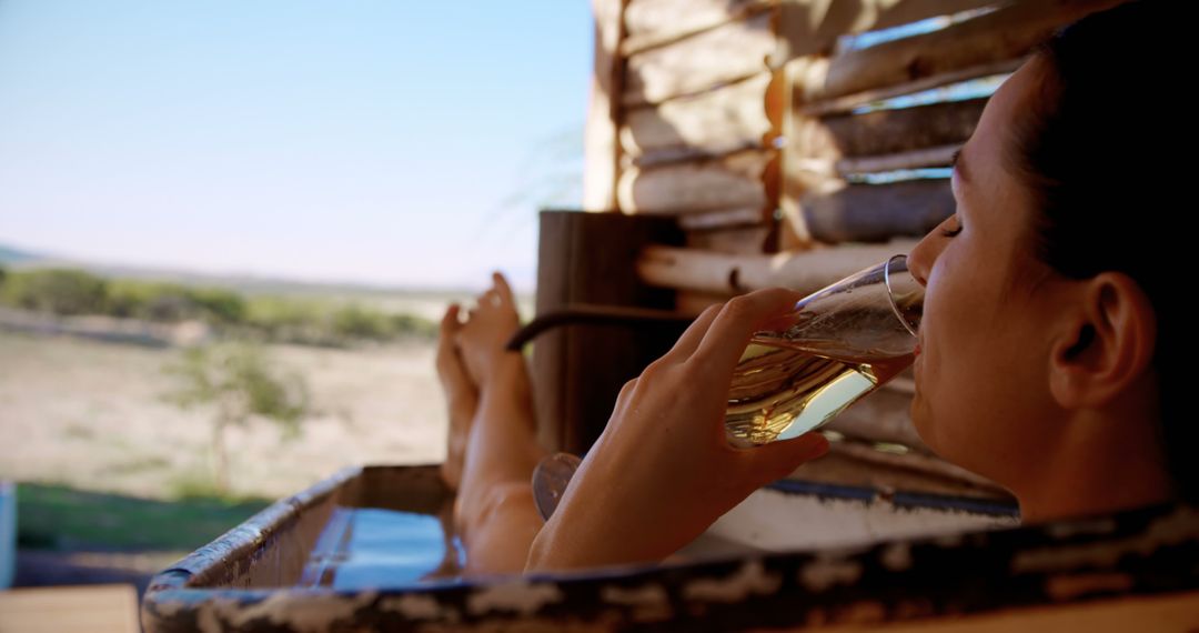 Woman Relaxing in Outdoor Bathtub with Beverage Enjoying Countryside View - Free Images, Stock Photos and Pictures on Pikwizard.com