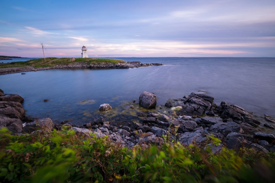 Serene Lighthouse Scene at Sunset with Rocky Shoreline - Free Images, Stock Photos and Pictures on Pikwizard.com