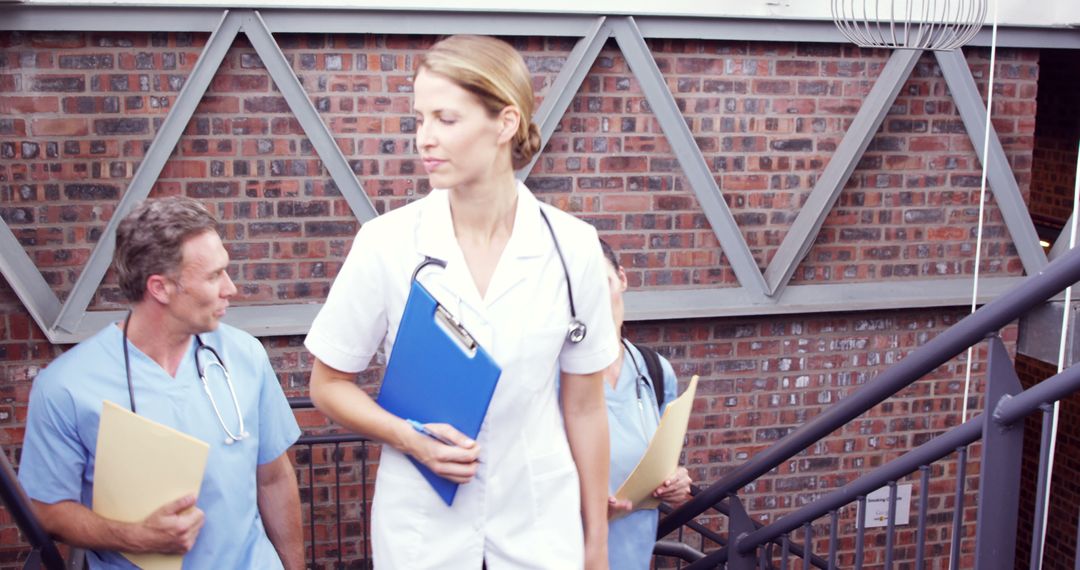 Medical Professionals Walking Down Stairs in Modern Hospital - Free Images, Stock Photos and Pictures on Pikwizard.com