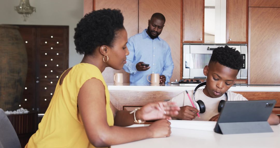 African American family sharing morning routine in kitchen while child studying on tablet