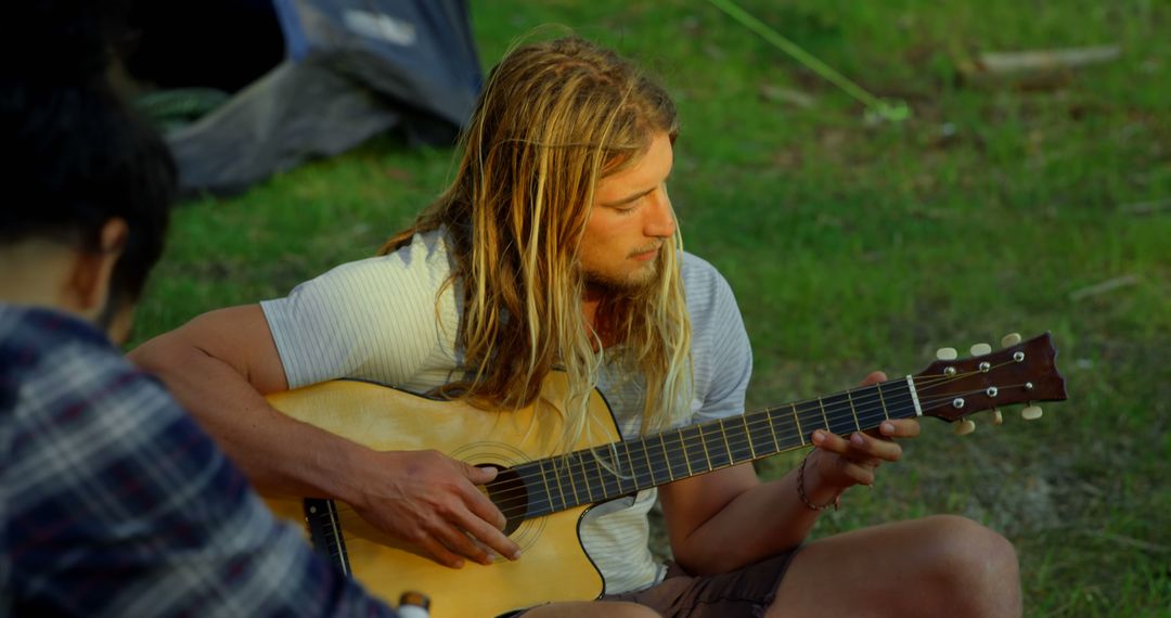 Man Playing Guitar Among Friends Relaxing at Forest Campground - Free Images, Stock Photos and Pictures on Pikwizard.com