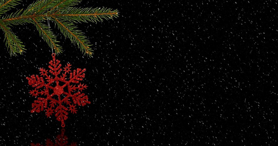 Red Snowflake Decoration on Pine Branch in Snowy Background