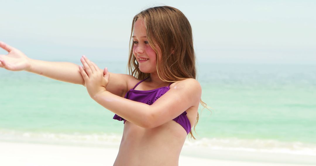 Happy Young Girl Playing on Beach in Purple Swimsuit - Free Images, Stock Photos and Pictures on Pikwizard.com