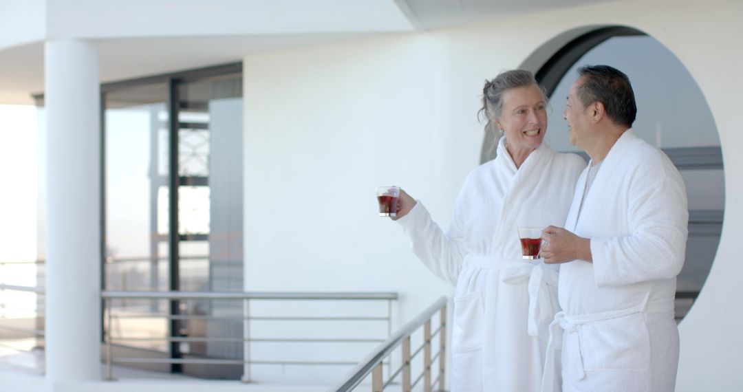 Senior Couple Enjoying Tea on Modern Balcony in Bathrobes