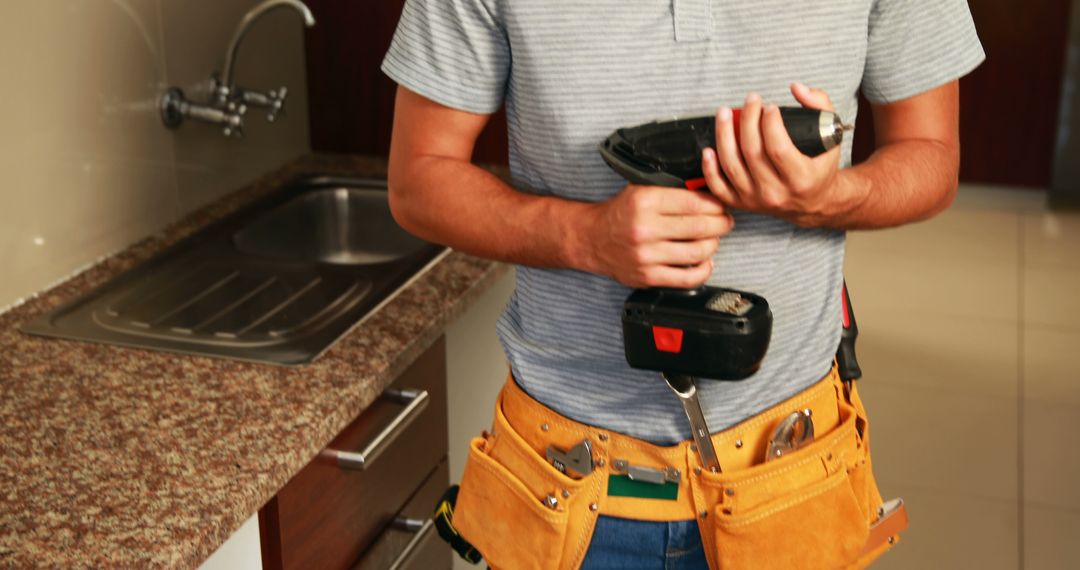 Plumber Holding Drill in Modern Kitchen - Free Images, Stock Photos and Pictures on Pikwizard.com