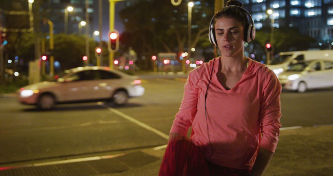 Female Runner Listening to Music with Headphones at Night City Intersection - Free Images, Stock Photos and Pictures on Pikwizard.com