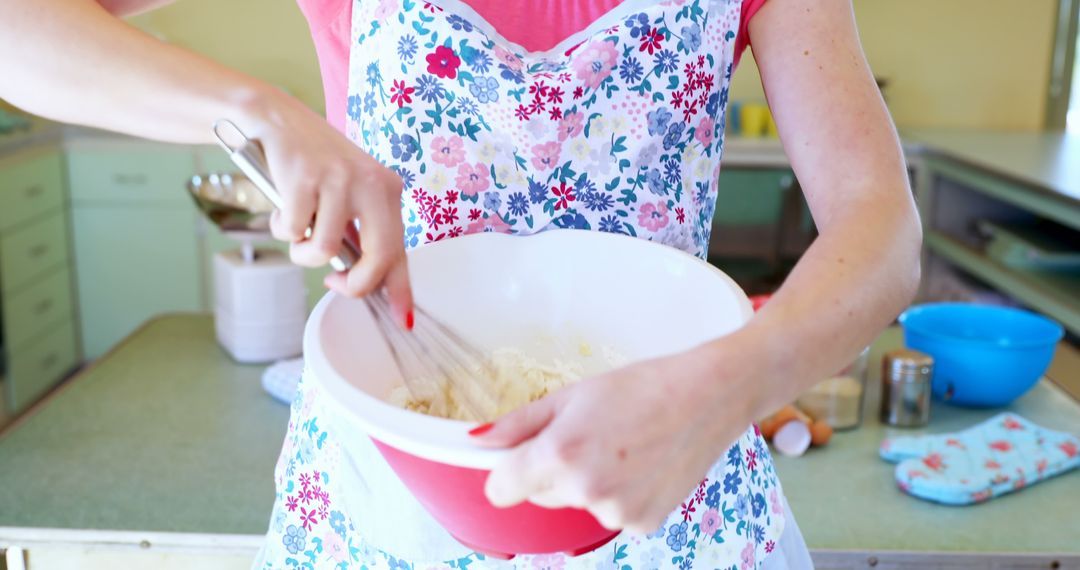 Close-up of Woman Whisking Ingredients in Kitchen with Floral Apron - Free Images, Stock Photos and Pictures on Pikwizard.com