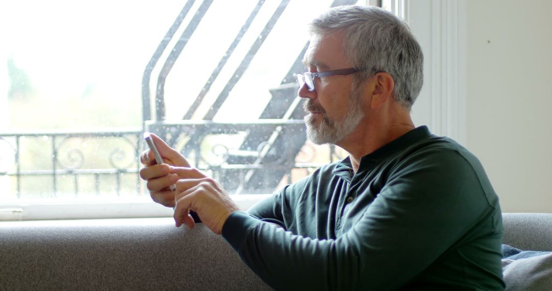 Senior Man Using Smartphone While Sitting on Sofa - Free Images, Stock Photos and Pictures on Pikwizard.com