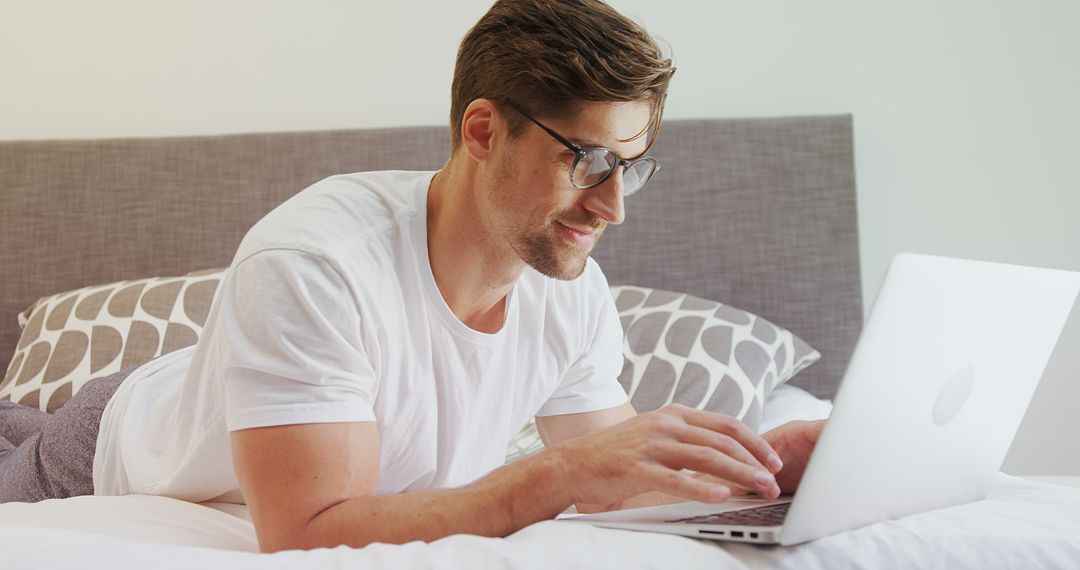 Man Using Laptop on Bed in Casual Setting - Free Images, Stock Photos and Pictures on Pikwizard.com