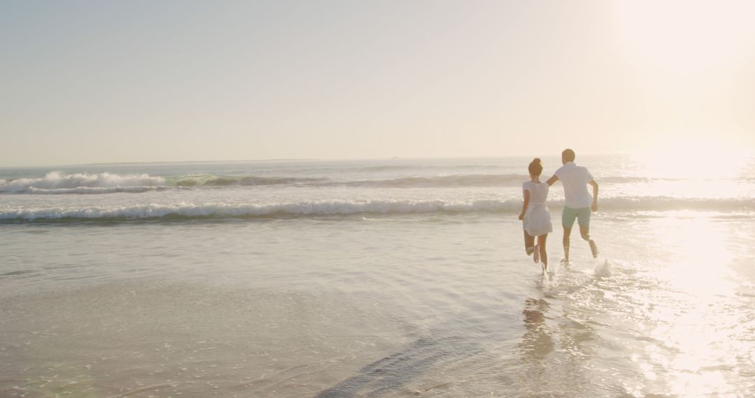 Couple Running on Beach in Sunlight - Free Images, Stock Photos and Pictures on Pikwizard.com