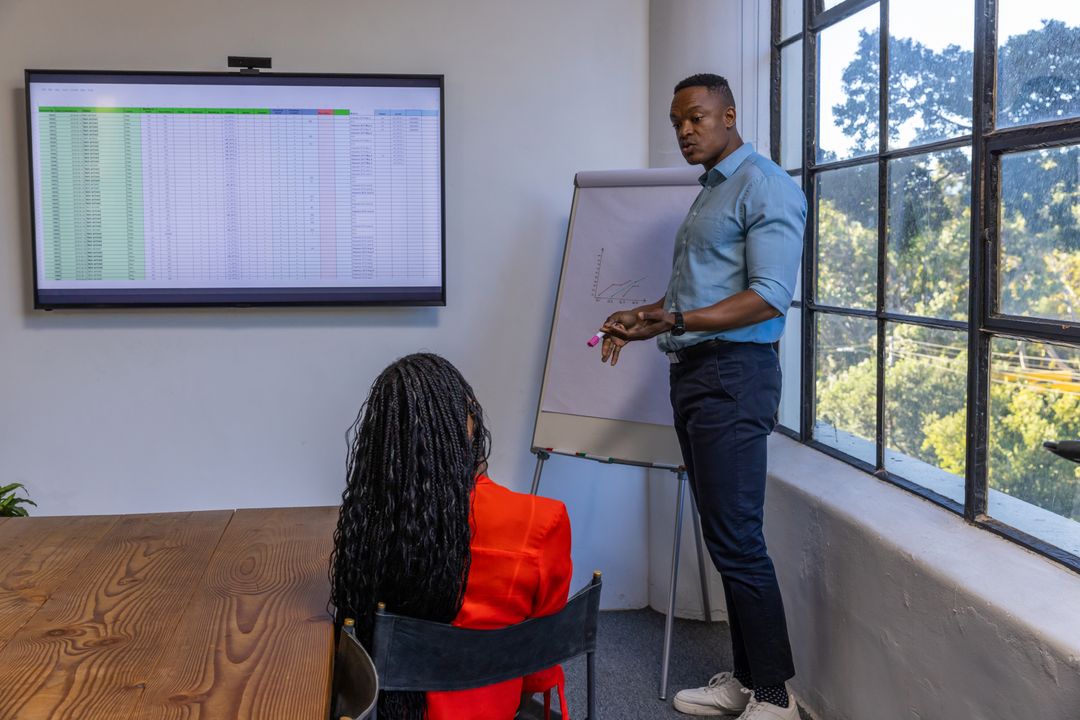 African American Colleagues Analyzing Graphic Presentation in Meeting Room