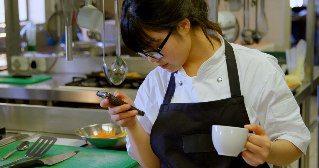 Chef Using Smartphone While Relaxing in Commercial Kitchen