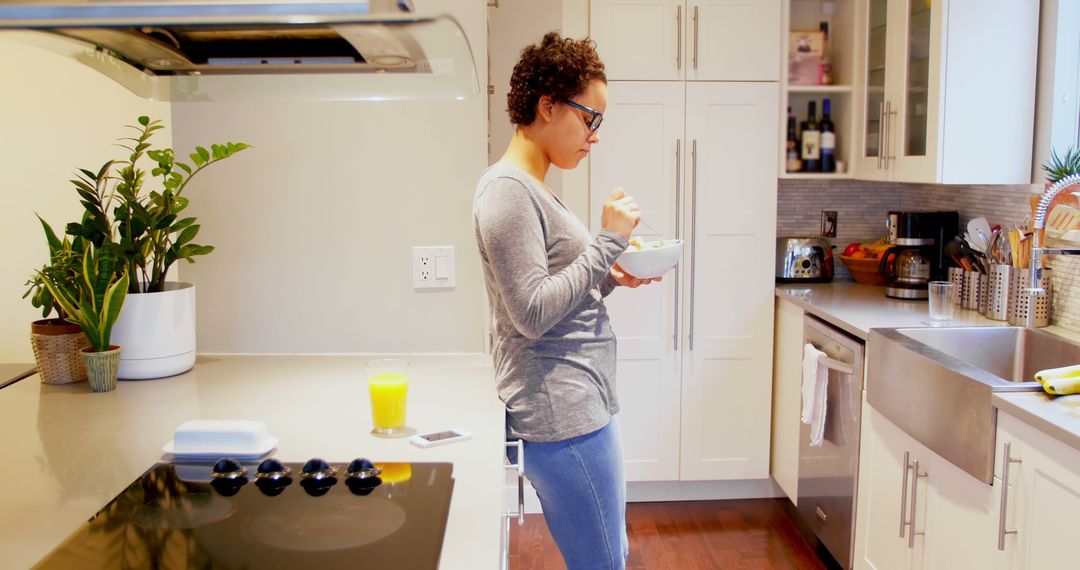 Young Woman Standing in Modern Kitchen Eating Breakfast - Free Images, Stock Photos and Pictures on Pikwizard.com