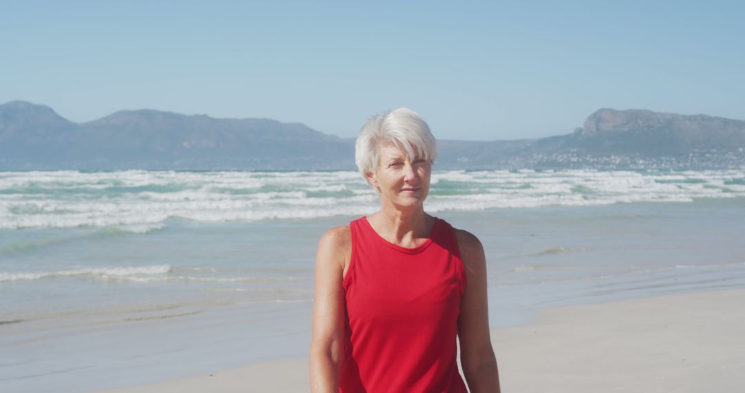 Senior Woman in Red Tank Top Enjoying Sunny Beach - Free Images, Stock Photos and Pictures on Pikwizard.com