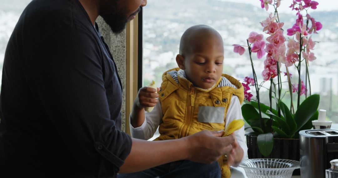 Father and Son Enjoying Bananas Together in Modern Kitchen
