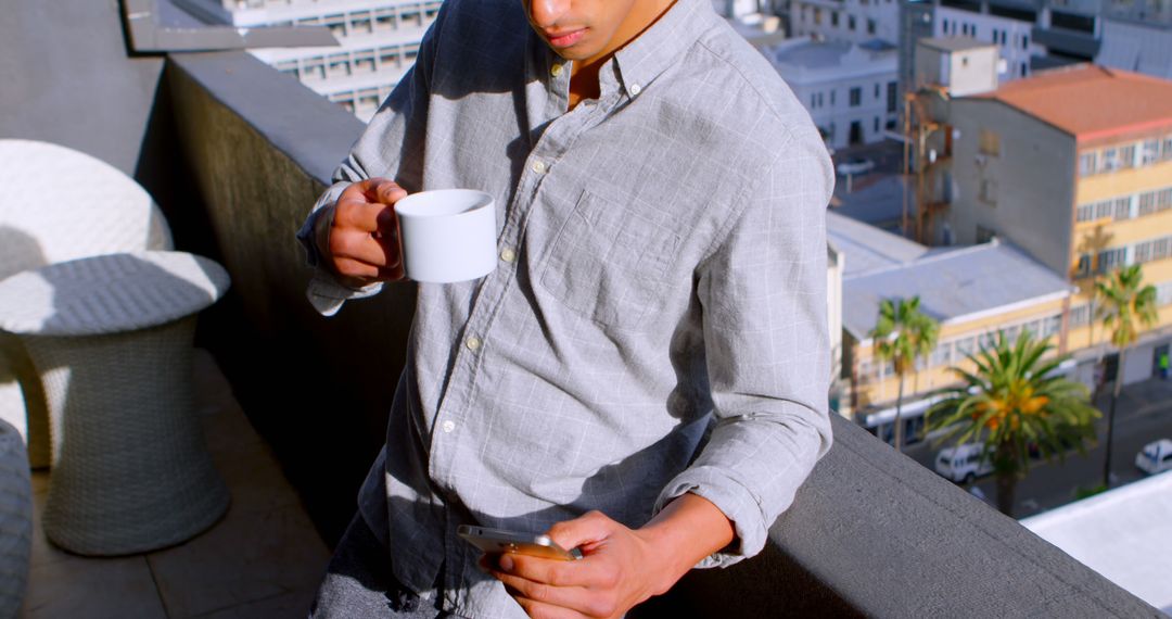 Man Drinking Coffee on Rooftop with City View, Using Smartphone - Free Images, Stock Photos and Pictures on Pikwizard.com