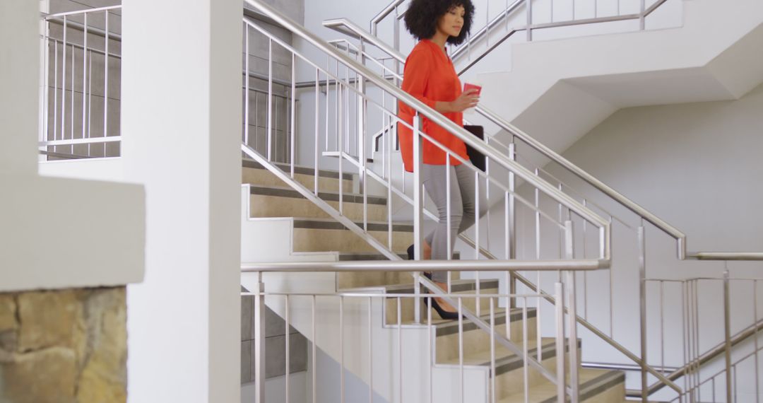 Businesswoman walking down stairs in modern office building - Free Images, Stock Photos and Pictures on Pikwizard.com