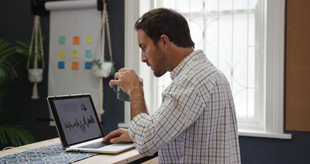 Man Working on Laptop in Home Office, Analyzing Data and Drinking Coffee - Free Images, Stock Photos and Pictures on Pikwizard.com