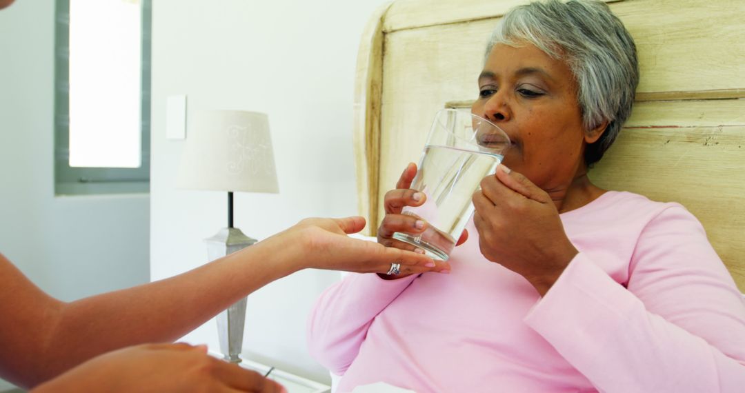 Elderly Woman Receiving Glass of Water in Bed - Free Images, Stock Photos and Pictures on Pikwizard.com