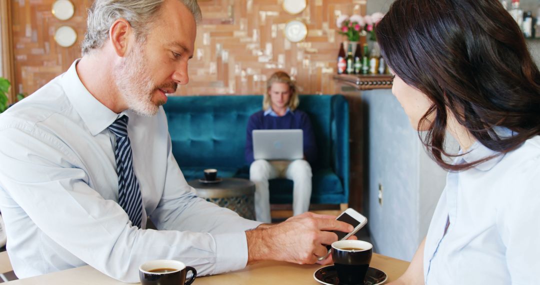Business Professions Discussing Smartphone Technology in Café Setting