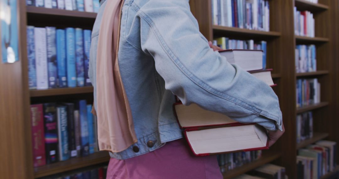 Person Carrying Stack of Books in Library with Bookshelves in Background - Free Images, Stock Photos and Pictures on Pikwizard.com