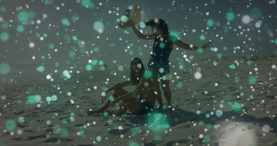 Young Couple Relaxing on Sandy Beach with Sunhat, Towel and Teal Bokeh Light Effects