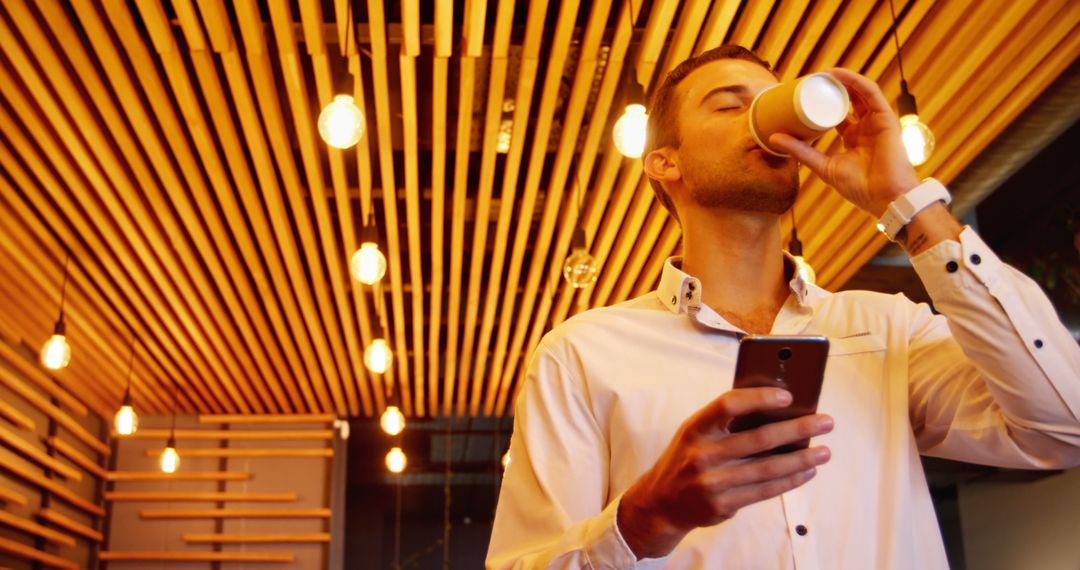 Man Drinking Coffee and Using Smartphone in Modern Coffee Shop - Free Images, Stock Photos and Pictures on Pikwizard.com