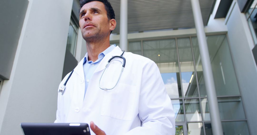 Confident Doctor Holding Tablet Outside Modern Hospital Building - Free Images, Stock Photos and Pictures on Pikwizard.com