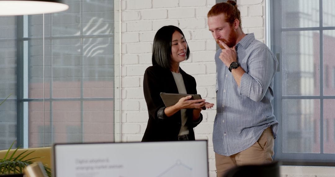 Diverse Professionals Collaborating on Tablet in Modern Office