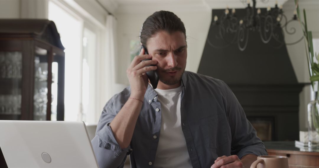 Focused Man on Smartphone Call While Working at Home