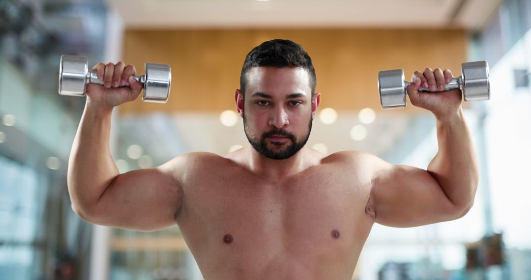 Muscular Man Lifting Dumbbells for Strength Training in Gym