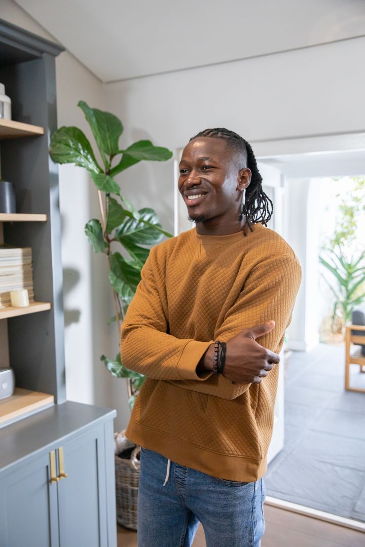 Smiling Man in Casual Outfit Relaxing at Modern Home with Plants