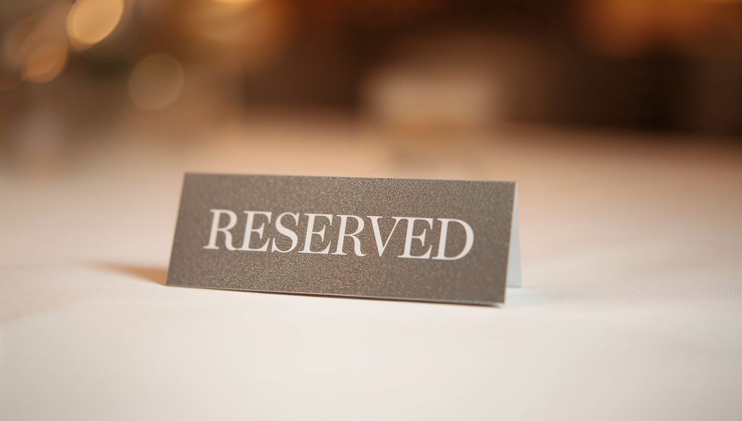 Reserved sign resting on white tablecloth at banquet with warm bokeh lights