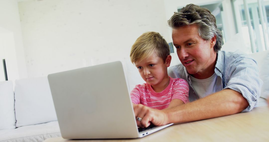 Middle-Aged Man Helping Young Boy with Laptop, Focused on Screen, Educational Family Moment - Free Images, Stock Photos and Pictures on Pikwizard.com