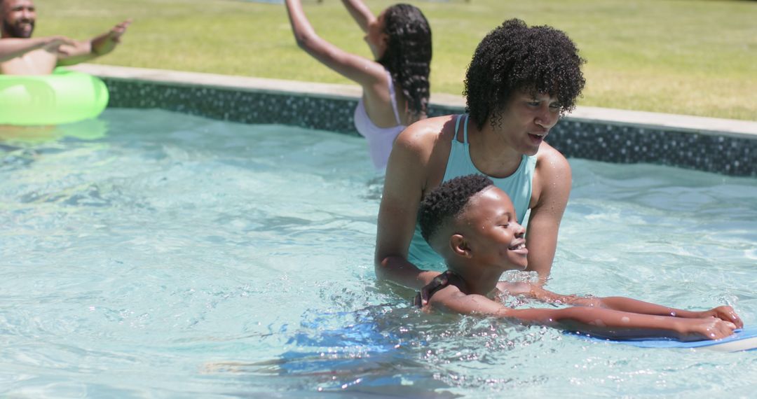 Mother Teaching Son to Swim in Sunny Pool with Float