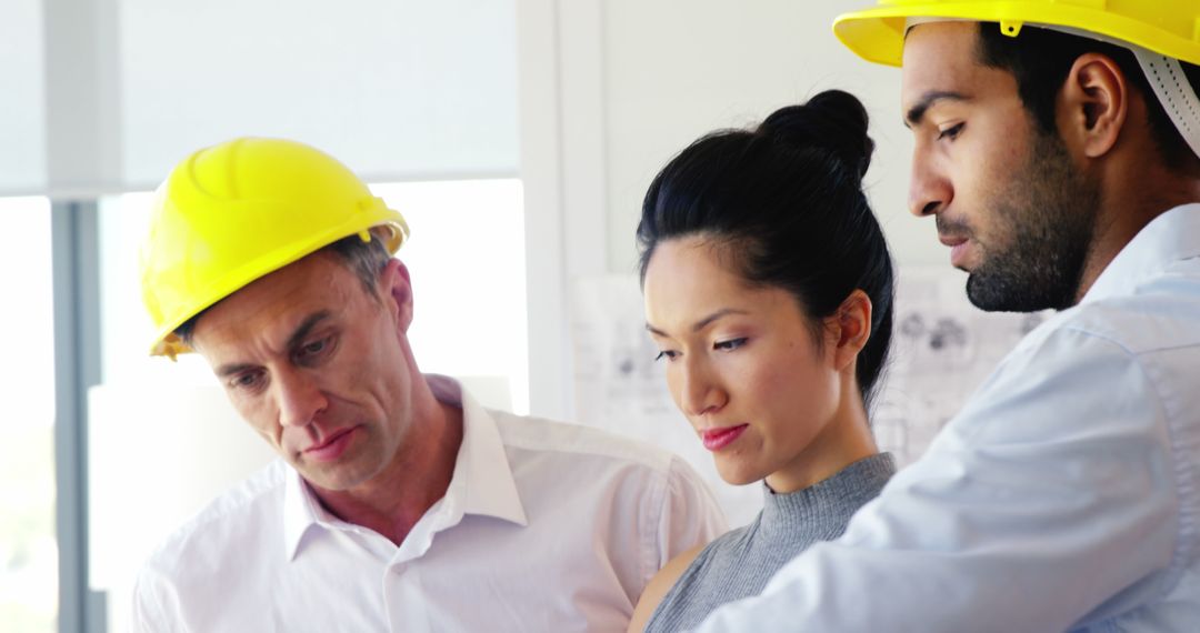 Multi-Ethnic Architects Analyzing Blueprint Together in Modern Office