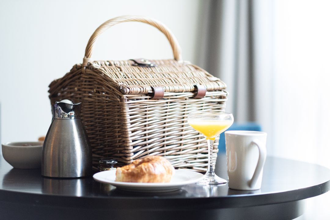 Breakfast Picnic Basket with Drink and Pastries on Table