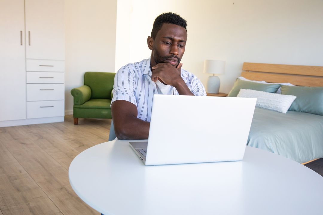 Focused Man Working on Laptop in Modern Homey Bedroom Setup