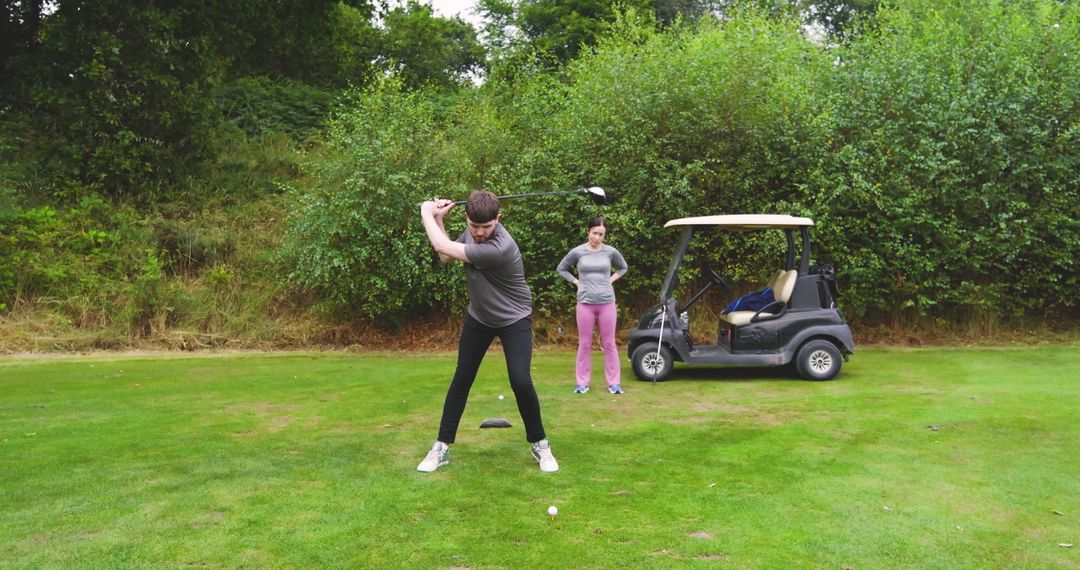 Couple Enjoying Golf Day on Green Course with Cart