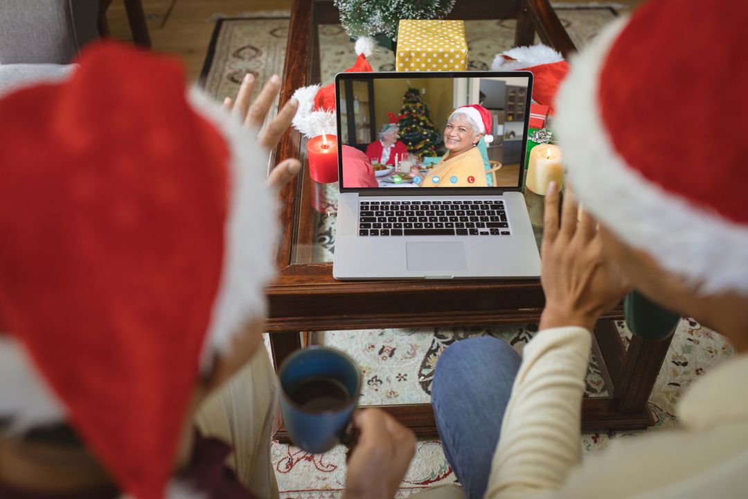 Diverse couple with santa hats having video call with happy biracial family - Free Images, Stock Photos and Pictures on Pikwizard.com