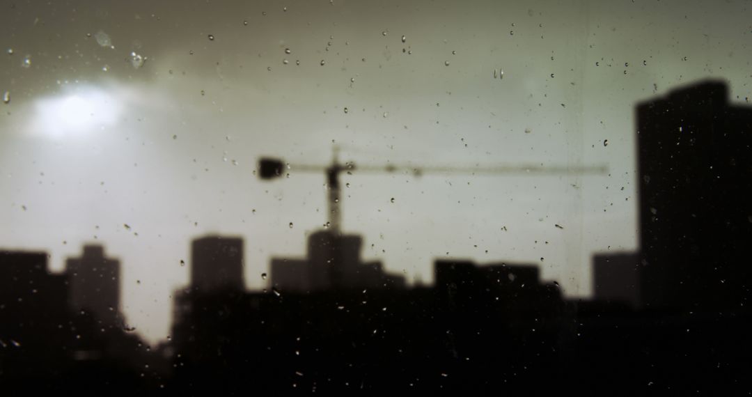 Rainy Cityscape with Silhouette of Construction Crane at Sunset - Free Images, Stock Photos and Pictures on Pikwizard.com