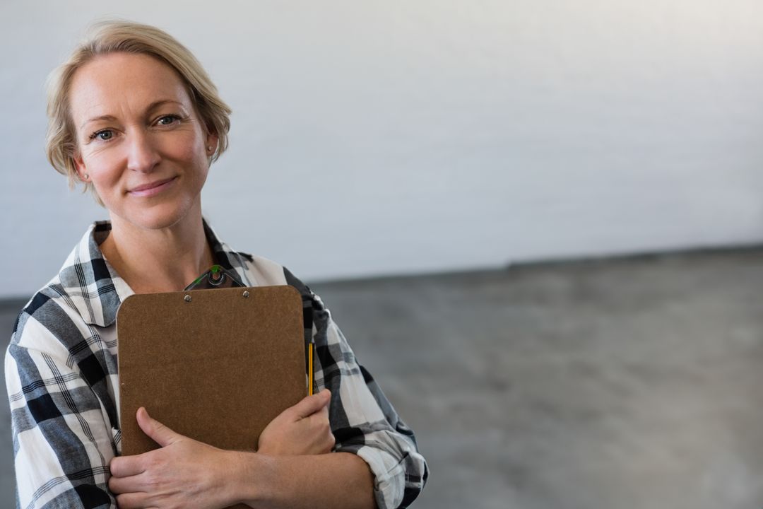 Confident Professional Woman Holding Clipboard in Empty Studio