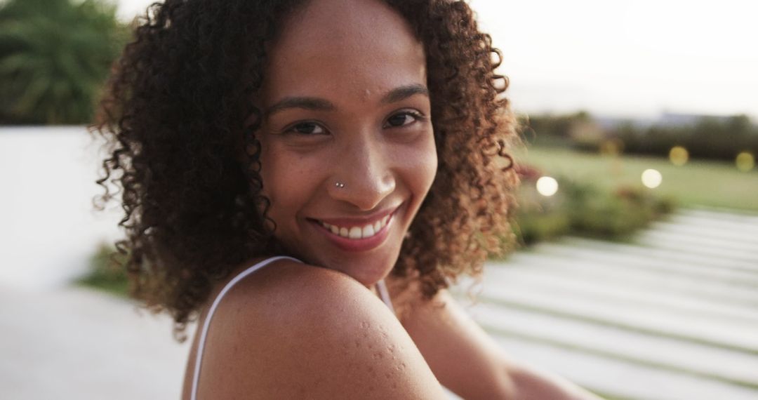 Smiling Woman with Curly Hair Looking at Camera Outdoors - Free Images, Stock Photos and Pictures on Pikwizard.com