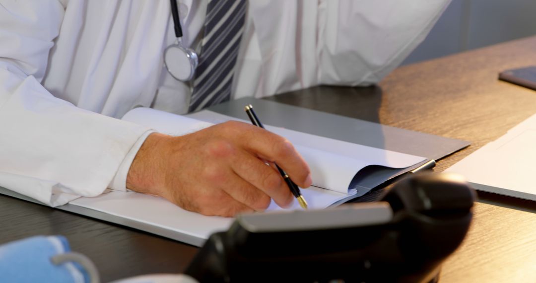 Doctor Writing in Notebook at Desk in Office - Free Images, Stock Photos and Pictures on Pikwizard.com