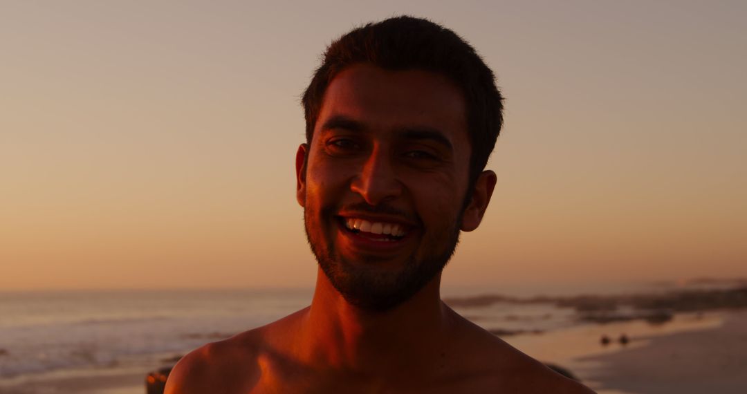 Portrait of happy biracial man with short black hair during sunset at beach - Free Images, Stock Photos and Pictures on Pikwizard.com