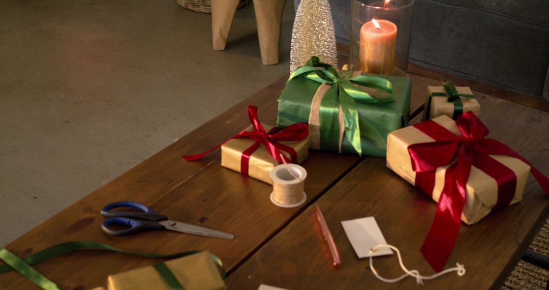 Cozy holiday gift wrapping scene on wooden table with ribboned presents and candlelight