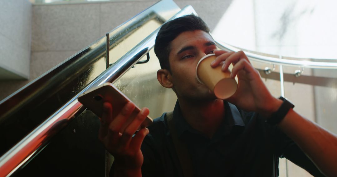 Young man drinking coffee while using smartphone outdoors - Free Images, Stock Photos and Pictures on Pikwizard.com