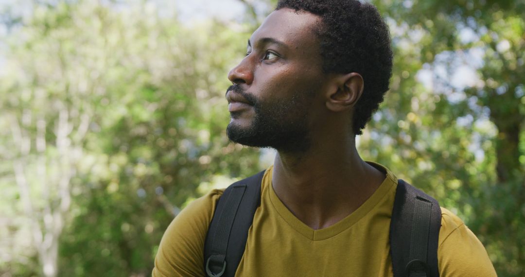 Thoughtful Man with Backpack in Lush Green Park