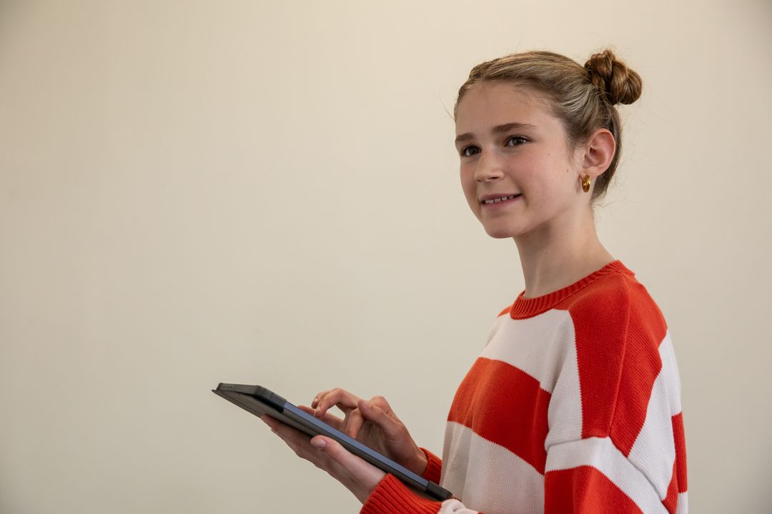 Cheerful Girl Using Tablet for Learning in Bright Casual Sweater